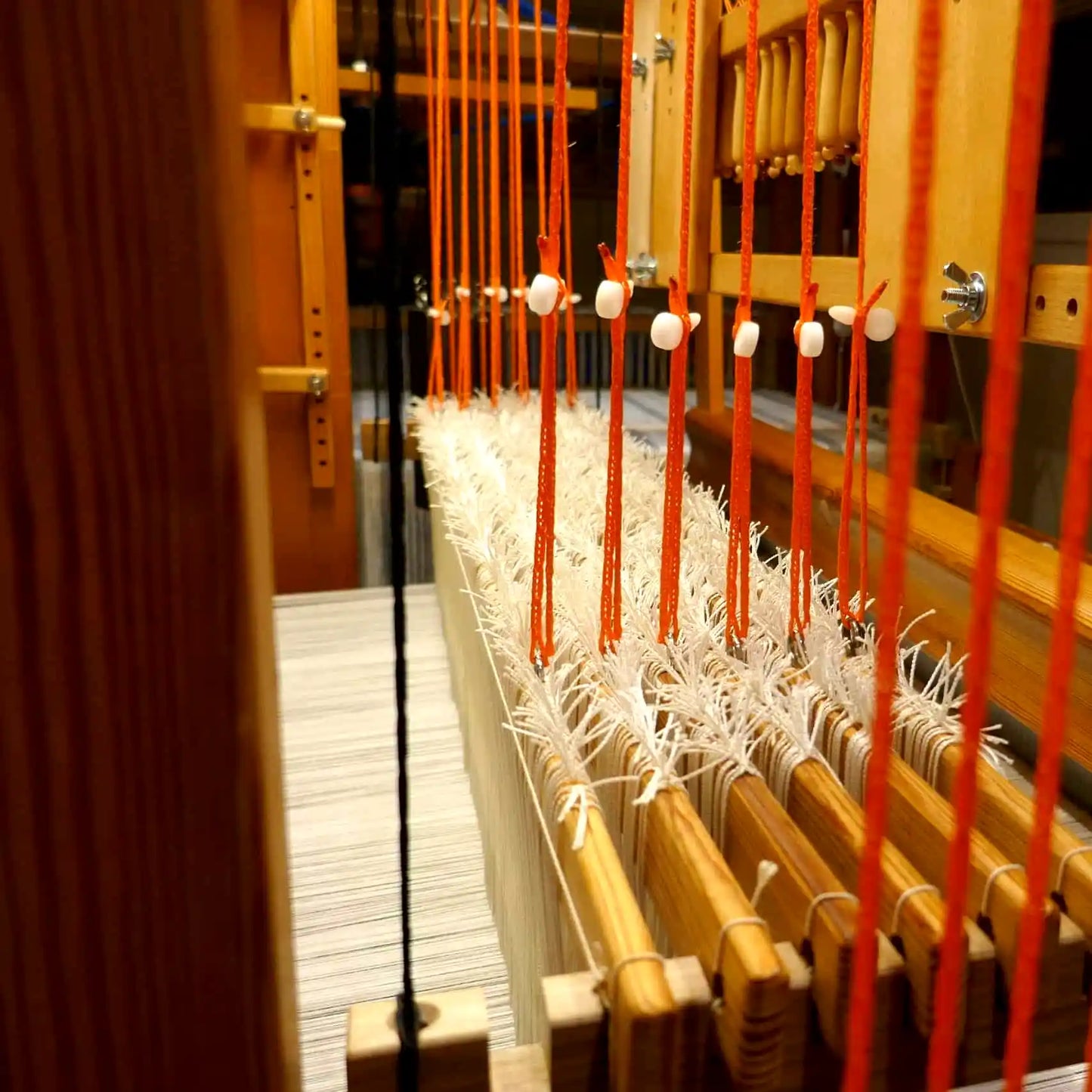 Orange Texsolv Schlaufenschnur mit weißen Clips in einem Webstuhl montiert – für präzise Schaftbindung